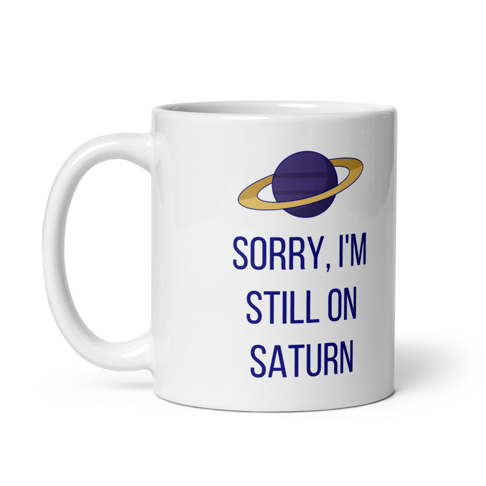 11 oz Saturn mug, handle on the left, showing the same gold-ringed planet and navy lettering printed on the other side