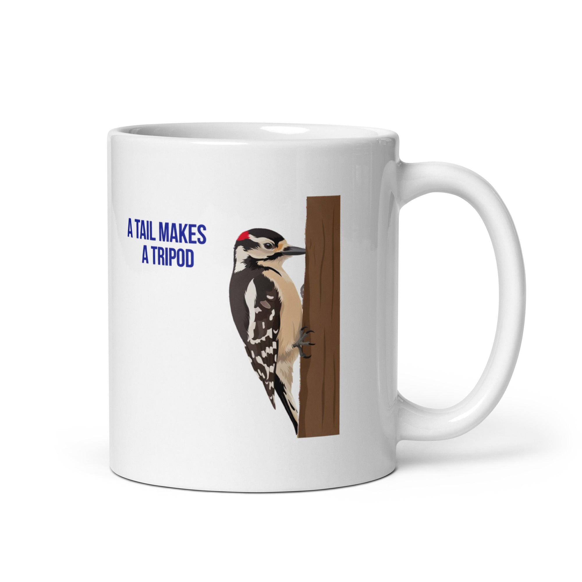 11 oz woodpecker mug, handle on the right, with A Tail Makes a Tripod in navy beside a Downy Woodpecker braced on a brown trunk