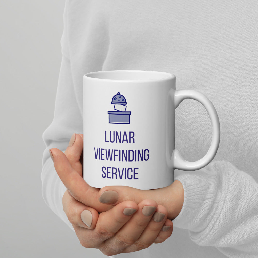 Lunar observer mug cradled in both hands against a light gray sweater, lunar dome and three rows of lettering visible