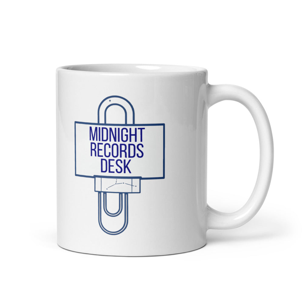 11 oz astronomy log mug, handle on the right, with MIDNIGHT RECORDS DESK on a navy desk sign held up by a paper clip
