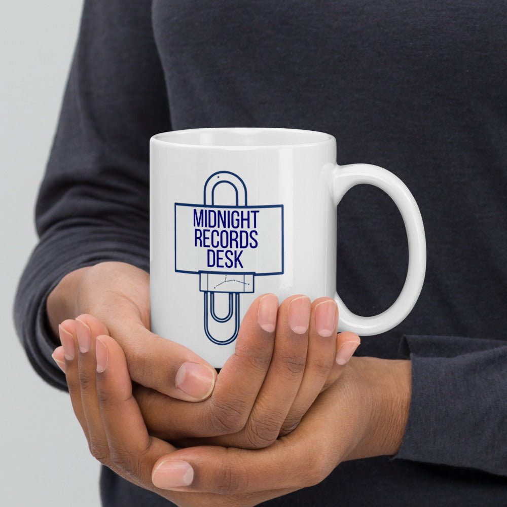 Hands cradling the 11 oz Midnight Records Desk mug, desk sign and paper clip facing out