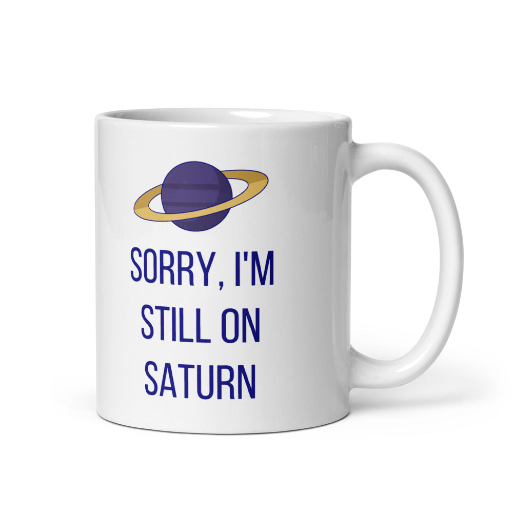11 oz Saturn mug, handle on the right, with SORRY, I'M STILL ON SATURN in navy under a purple Saturn with a gold ring