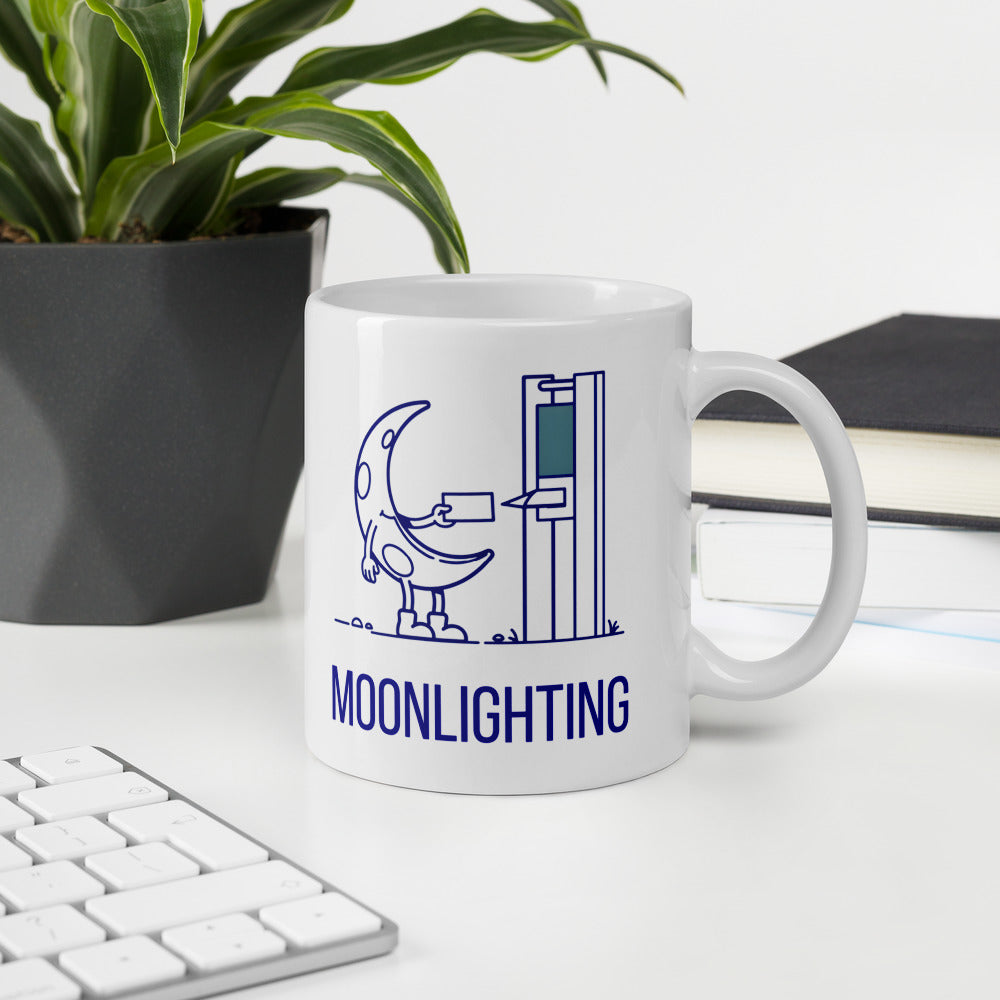 Moonlighting moon mug on a white desk beside a keyboard, a plant and a stack of books