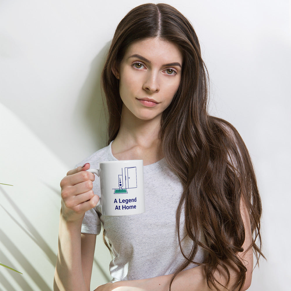 Woman holding the 11 oz A Legend at Home mug, the chart legend and open door above the navy lettering